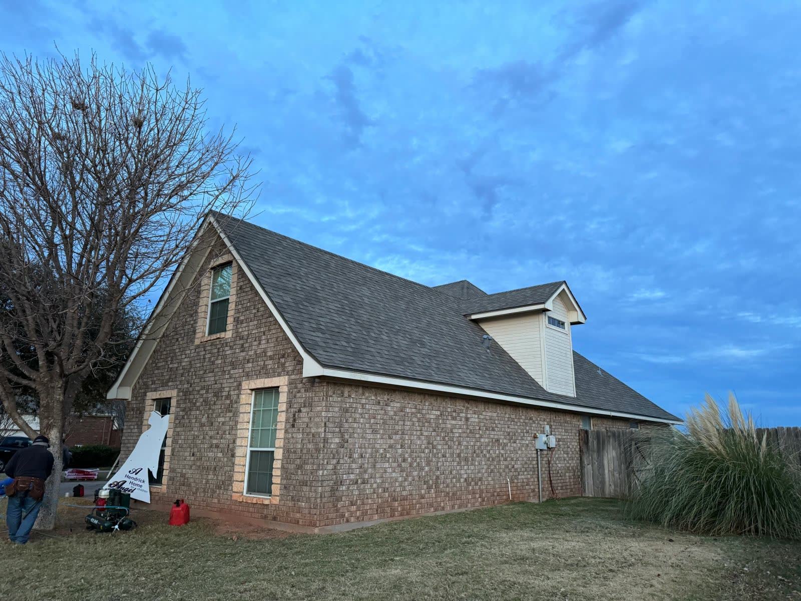 Brick home with a tall gable and a grey shingle roof