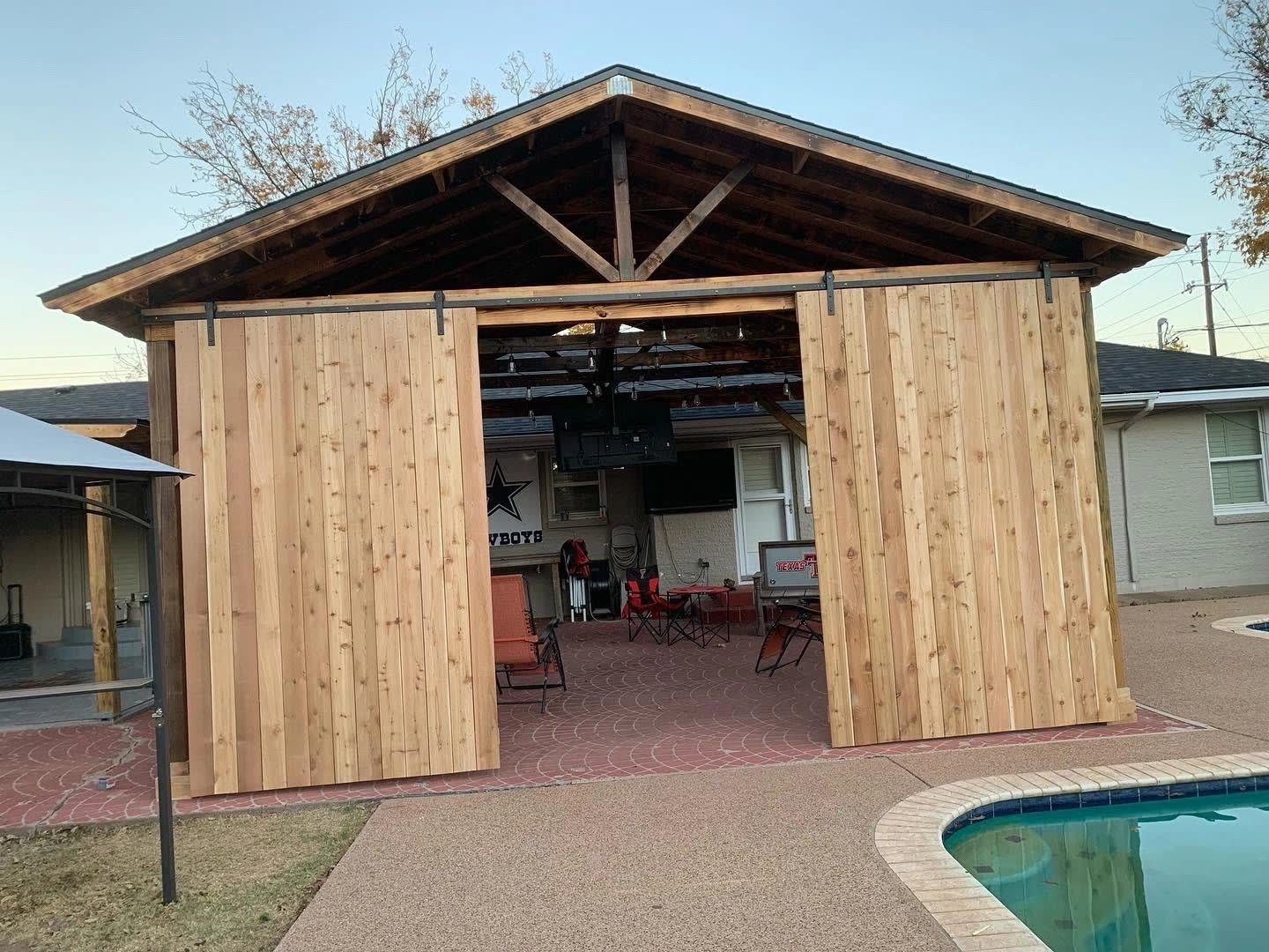 Cedar pavilion with sliding barn doors beside a backyard pool