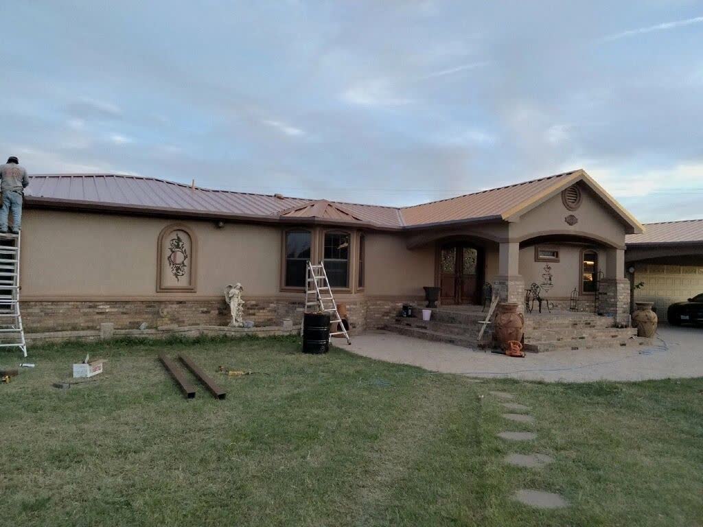 Stucco ranch house with a new metal roof, crew up on the ladders